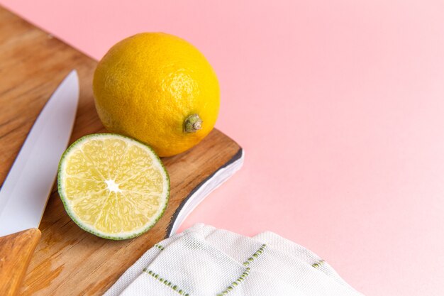 front-view-fresh-lemon-with-sliced-lime-pink-wall_140725-42294